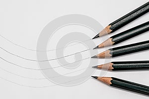 Black pencils in different degrees of hardness on white paper