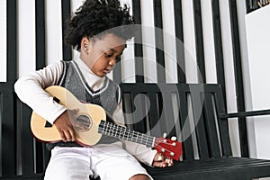 Black people African American child hold ukulele and look at camera with smile