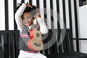 Black people African American child hold ukulele and look at camera with smile