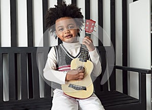 Black people African American child hold ukulele and look at camera with smile