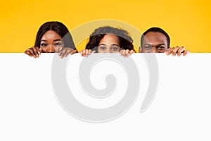 Black people peeking out blank white advertising billboard at studio