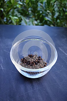 Black pepper in bowl on black background