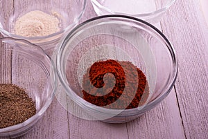 Black pepper, garlic powder, salt, and chili powder in separate glass bowls on a light background