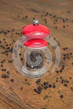 Black pepper and manual mill on wooden background