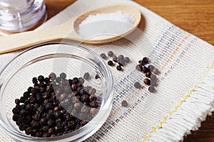 black pepper peas in a glass bowl on a linen napkin, salt mill on a wooden kitchen table