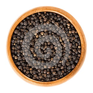 Black pepper in wooden bowl over white