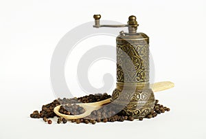 Black pepper, wooden spoon and vintage mill on white background. Spice grinder and heap of grains of pepper. Sample