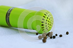 Black peppercorns in ancient metal mortar with pestle on linen background