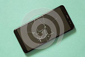 Black phone with cracked screen on an isolated background close-up
