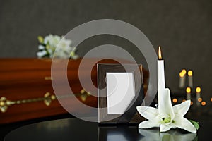Black photo frame with burning candle and  lily on table in funeral home