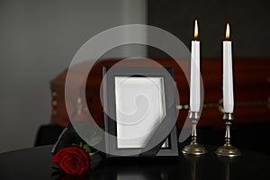 Black photo frame with  candles and red rose on table in funeral home