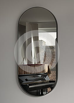A black piano by the window reflecting in the Capsula pill shaped mirror on white wall photo