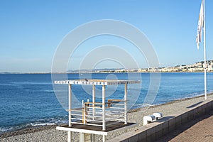 A black pigeons sits atop a Poste de Secours, or First Aid Station on the empty beach of the Bay of Angels on the French Riviera photo