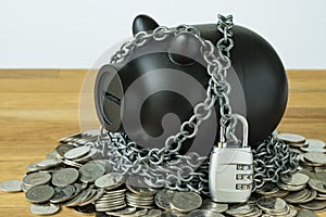 Black piggy bank with chains and lock pad on top of coins as sec