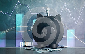 Black piggy bank with money on grey table. Illustration of financial graphs