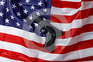 A black pistol lies against the background of the American flag. Personal weapons of the population. Close-up