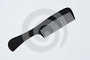 Black plastic comb lies on a white background. Isolate