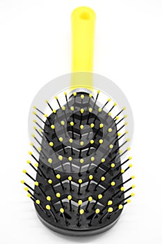 Black plastic comb with a yellow handle