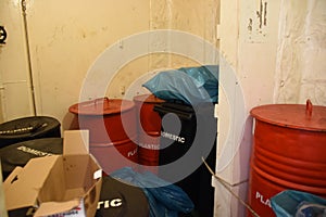 Black plastic containers and red metal drums as garbage bins inside superstructure. photo