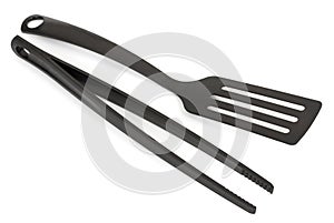 Black plastic cooking tongs and spatula isolated on white background