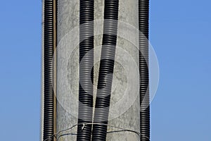 Black plastic hoses with electrical cables on a gray concrete pillar