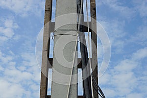 Black plastic hoses with electrical cables on a gray concrete pillar