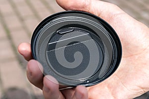 Black plastic lid of a coffee mug, covered with drops of condensation