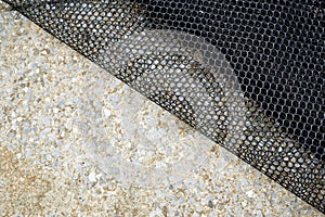 A black plastic net on the cement floor, abstract background and texture for design
