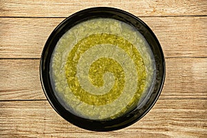 a black plate of fresh vegetable green cream soup served on rustic background