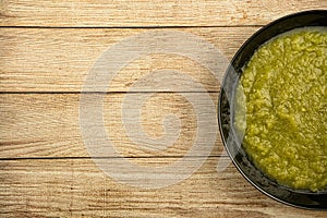 a black plate of fresh vegetable green cream soup served on rustic background