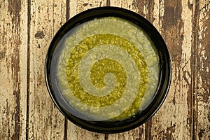 a black plate of fresh vegetable green cream soup served on rustic background