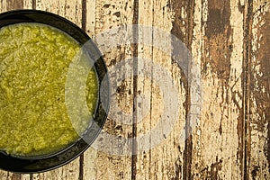 a black plate of fresh vegetable green cream soup served on rustic background