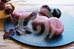 Black plate with purple balls and leaves, perfect for serving natural foods. Mochi asian dessert