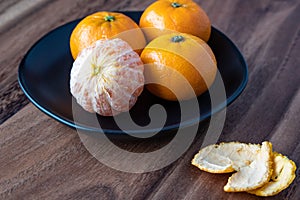 Black plate of satsuma oranges on a rustic wood table