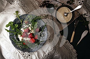 Black plate with strawberry on old white lace tablecloth.