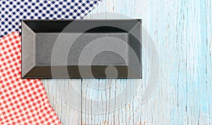 Black plate on tablecloth on wood table background