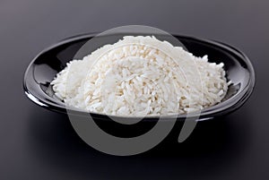 A black plate with white rice on a black background