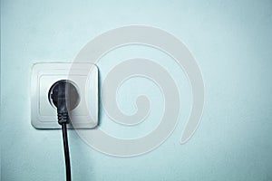 Black plug inserted in electrical outlet.