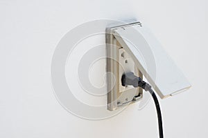 Black plug plugged in a socket with cover