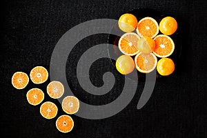 A composition of cut in halves oranges and tangerines on a black background