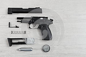 Black pneumatic pistol (air gun) gun unassembled on a lighten ba