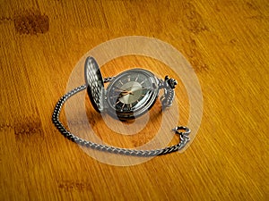 Black pocket watch resting on wood table