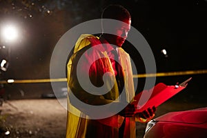 Black Police Office Reading Documents at Crime Scene photo