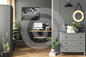 Black poster on grey wall above desk with mockup in home office interior with mirror. Real photo