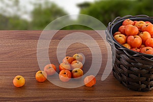 Black pot with acerolas on table and some fallen acerolas
