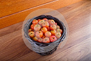 Black pot with acerolas on table.
