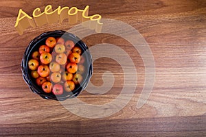 Black pot with acerolas on table - top view