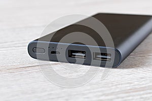 Black power Bank for charging mobile devices on wooden table