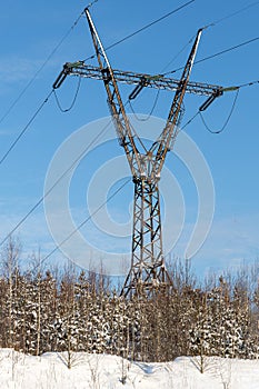 Black power line is on the blue sky background. Winter landscape. Vertical