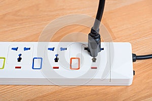 Black power line plug in white socket electric power bar